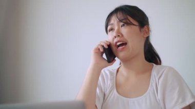Evdeki oturma odasında Asyalı bir kadın telefonda konuşuyor..