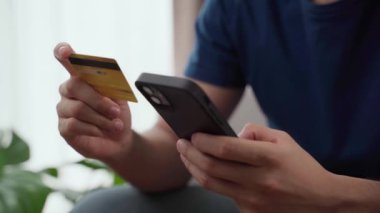 Bir adam cep telefonunu kredi kartıyla ödeme yapmak için kullanıyor. Kolaylık ve modernlik kavramı, çünkü adam telefonunu kullanarak bir işlemi tamamlayabiliyor.