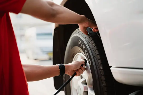 A man is sitting on the ground and inflating a tire with a tire inflator. Concept of urgency and the importance of maintaining proper tire pressure for safe driving