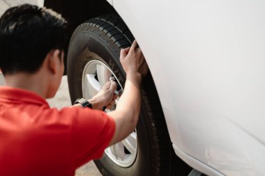 Bir adam yerde oturuyor ve lastiği şişirerek şişiriyor. Acil durum kavramı ve güvenli sürüş için uygun lastik basıncının korunmasının önemi