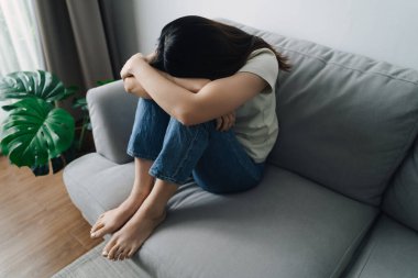 Mutsuz, bunalımlı kadın koltukta oturuyor ve elleriyle yüzünü kapatıyor. Depresyon kavramı.