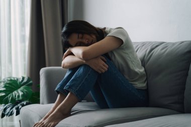 Mutsuz, bunalımlı kadın kanepede oturuyor. Üzgün ve yorgun görünüyor..