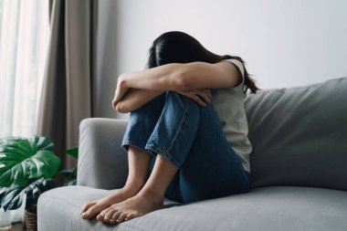 Depresyonda olan bir kadın kanepede başı eğik oturuyor. Üzgün ya da üzgün..