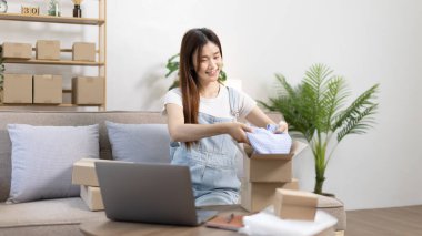 Kadın posta kutusunu paketleyip müşteriye teslim etmeye hazırlanıyor, evde çalışıyor ve işletme sahibi oluyor, çevrimiçi alışveriş yapan KOBİ girişimcisi, paketleme kutusu, çevrimiçi satış, serbest çalışma.