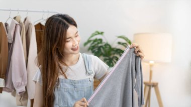 Sosyal medya etkisine sahip güzel bir kadın stüdyosunda ucuz moda kıyafetleri satarak canlı ya da kayıt gösterileri yapıyor, video canlı yayın, Online moda giyim sektörü.