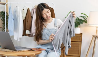 Sosyal medya etkisine sahip güzel bir kadın stüdyosunda ucuz moda kıyafetleri satarak canlı ya da kayıt gösterileri yapıyor, video canlı yayın, Online moda giyim sektörü.