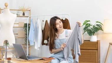 Sosyal medya etkisine sahip güzel bir kadın stüdyosunda ucuz moda kıyafetleri satarak canlı ya da kayıt gösterileri yapıyor, video canlı yayın, Online moda giyim sektörü.