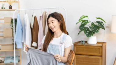 Sosyal medya etkisine sahip güzel bir kadın stüdyosunda ucuz moda kıyafetleri satarak canlı ya da kayıt gösterileri yapıyor, video canlı yayın, Online moda giyim sektörü.