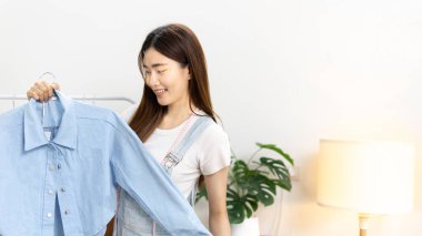 Sosyal medya etkisine sahip güzel bir kadın stüdyosunda ucuz moda kıyafetleri satarak canlı ya da kayıt gösterileri yapıyor, video canlı yayın, Online moda giyim sektörü.