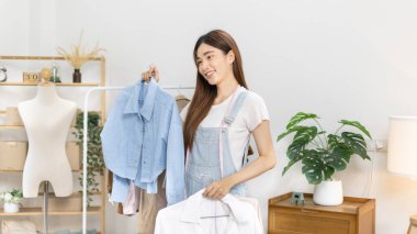 Sosyal medya etkisine sahip güzel bir kadın stüdyosunda ucuz moda kıyafetleri satarak canlı ya da kayıt gösterileri yapıyor, video canlı yayın, Online moda giyim sektörü.