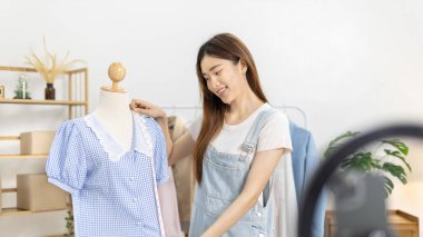 Sosyal medya etkisine sahip güzel bir kadın stüdyosunda ucuz moda kıyafetleri satarak canlı ya da kayıt gösterileri yapıyor, video canlı yayın, Online moda giyim sektörü.