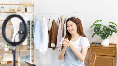 Sosyal medya etkisine sahip güzel bir kadın, seyirciyi video canlı yayını, çevrimiçi moda giyim sektörü, müşterilere ilgi göstermek için psikolojiyi kullandıkları için selamlıyor..