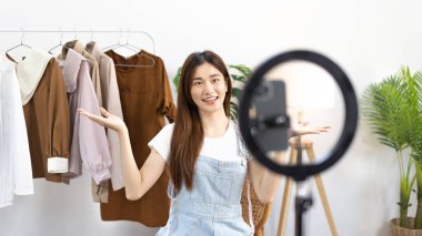 Sosyal medya etkisine sahip güzel bir kadın, seyirciyi video canlı yayını, çevrimiçi moda giyim sektörü, müşterilere ilgi göstermek için psikolojiyi kullandıkları için selamlıyor..