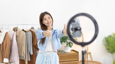 Sosyal medya etkisine sahip güzel bir kadın, seyirciyi video canlı yayını, çevrimiçi moda giyim sektörü, müşterilere ilgi göstermek için psikolojiyi kullandıkları için selamlıyor..