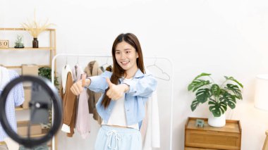 Sosyal medya etkisine sahip güzel bir kadın, seyirciyi video canlı yayını, çevrimiçi moda giyim sektörü, müşterilere ilgi göstermek için psikolojiyi kullandıkları için selamlıyor..