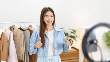 Sosyal medya etkisine sahip güzel bir kadın, seyirciyi video canlı yayını, çevrimiçi moda giyim sektörü, müşterilere ilgi göstermek için psikolojiyi kullandıkları için selamlıyor..