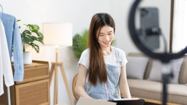 Kadın, internetten ya da uygulamadan sipariş veren müşterilerle sohbet etmek için tablet kullanıyor, evde serbest çalışıyor, kıyafetleri hem perakende hem toptan satıyor, internette satıyor, küçük işletme sahibi, KME girişimcisi.