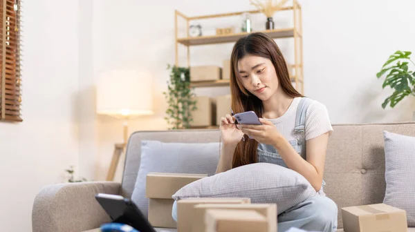 Woman uses mobile phone or tablet to chat with customers who come to order product, Freelance work at home, Conversation with customers through massage, Small business owner, SME entrepreneur.