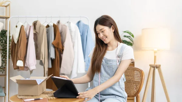 Woman uses a tablet to chat with customers ordering online or on an app, Freelance work at home, Sell clothes online both retail and wholesale, Sell online, Small business owner, SME entrepreneur.