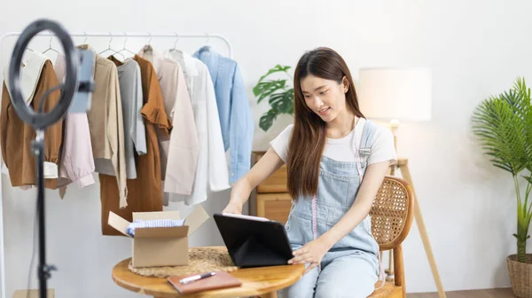 stock image Woman uses a tablet to chat with customers ordering online or on an app, Freelance work at home, Sell clothes online both retail and wholesale, Sell online, Small business owner, SME entrepreneur.