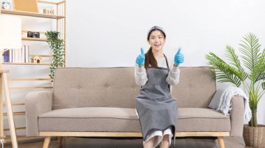 Önlük ve temizlik eldivenleri giyen güzel Asyalı ev hanımı evini, ev işlerini, günlük rutinini, büyük temizliği, evdeki mikropları temizleyip temizlemeye hafta sonları temizlik yapmaya hazırlanıyor..