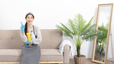Önlük ve temizlik eldivenleri giyen güzel Asyalı ev hanımı evini, ev işlerini, günlük rutinini, büyük temizliği, evdeki mikropları temizleyip temizlemeye hafta sonları temizlik yapmaya hazırlanıyor..