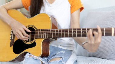 Gitar telleri çalan parmakları kapat, gitar çalmak için Strum, akustik gitar, müzik yapmak için gitar akorları yakalamak, müzik terapisi ve gitar çalarak meditasyon pratiği.