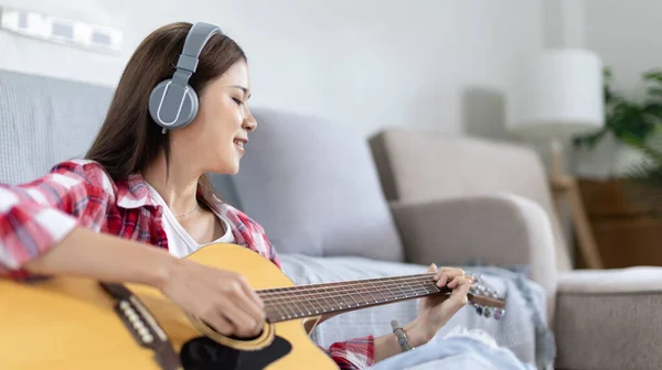 stock image Woman practicing or learning to play guitar and practice using his fingers to hold guitar chords while looking at music notes with intention, Taking advantage of free time, Relax during free time.