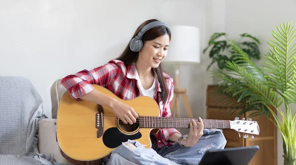 stock image Woman practicing or learning to play guitar and practice using his fingers to hold guitar chords while looking at music notes with intention, Taking advantage of free time, Relax during free time.
