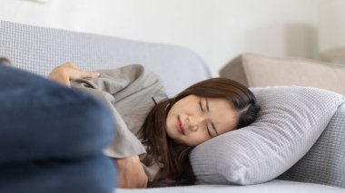 Kanepede yüksek ateşle titreyen bir kadın, şiddetli bir hastalık, baş ağrısı, boğaz ağrısı, yüksek ateş, fiziksel sağlığınıza dikkat etmemek ve egzersiz yapmamak bağışıklık sisteminizin düşük olmasına neden olur.