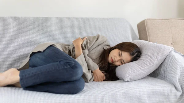 Woman lying chills with high fever on sofa, Severe illness, Headache, Sore throat, High fever, Not taking care of your physical health and not exercising causes your immune system to be low