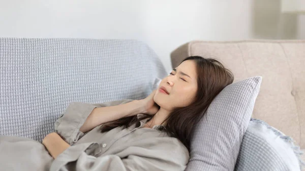 Woman lying chills with high fever on sofa, Severe illness, Headache, Sore throat, High fever, Not taking care of your physical health and not exercising causes your immune system to be low