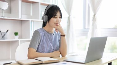 Genç Asyalı kadınlar video sohbetleri yoluyla arkadaşlarını ve öğretmenlerini selamlıyor ve onları neşeli ifadelerle karşılıyor, İnternet iletişimi, Evde kal, Yeni Normal, VDO Çağrısı, Sosyal Mesafe, İnternet öğrenimi.