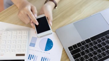 Finans çalışanları şirketin finansal verilerini bir dizüstü bilgisayarda inceliyor ve sosyal mesafelerde ekiple iletişim kurmak veya sohbet etmek için akıllı telefonları kullanıyor, özel bir ofiste tek başlarına çalışıyorlar..