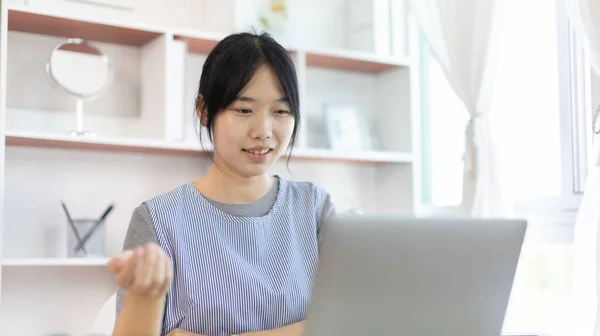 Young Asian women are greeting friends and teachers through video chats and greeting them with cheerful expressions, Online communication , Stay home, New normal, VDO Call, Social distancing, Internet learning.