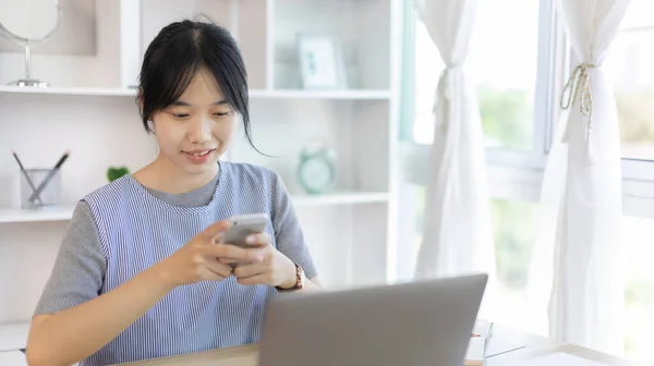 Asian woman having fun playing games on mobile phone, Play games on the sofa in the living room on weekends, Resting at home, Comfort zone, Touch screen mobile phone.