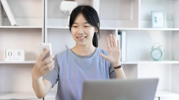Young Asian women are greeting friends and teachers through video chats and greeting them with cheerful expressions, Online communication , Stay home, New normal, VDO Call, Social distancing, Internet learning.