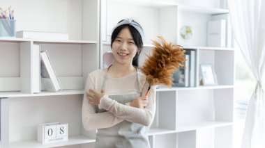 Yastıkları, halıları ve diğer şeyleri temizlemek için elinde fırça tutan ev hanımı.