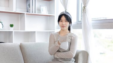 Oturma odasındaki eşyaları temizlemek için elinde sprey şişesi olan genç bir ev hanımı büyük temizlik, ev işi, günlük rutin temizlik mikropları, kirleri ve derin lekeleri temizler..