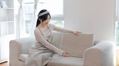 Genç ev hanımı kanepeyi temizliyor, oturma odasını temizliyor, evdeki büyük temizlik mikropları, kirleri ve derin lekeleri temizliyor, ev hanımı temizliyor, evini temiz tutuyor, evdeki hijyeni temizliyor.. 