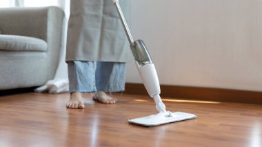 Genç ev hanımı ahşap zemini paspaslıyor ve temizliyor oturma odasını temizlemek için antiseptik paspas kullanıyor ev ödevlerini yapıyor ev kadınlarının görevlerini yapıyor profesyonel sağlık hizmetleri kavramını kullanıyor..