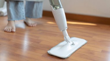 Genç ev hanımı ahşap zemini paspaslıyor ve temizliyor oturma odasını temizlemek için antiseptik paspas kullanıyor ev ödevlerini yapıyor ev kadınlarının görevlerini yapıyor profesyonel sağlık hizmetleri kavramını kullanıyor..