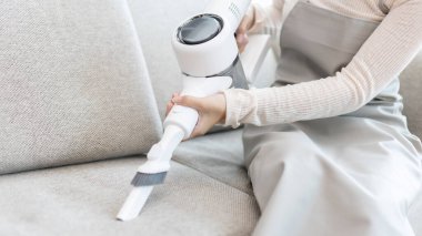 Güzel bir kadın oturma odasındaki kanepeyi ve yastığı süpürüyor, evdeki büyük temizlik mikropları, kirleri ve lekeleri temizliyor, ev kadınını temizliyor, evini temiz tutuyor, evdeki hijyenini temiz tutuyor..