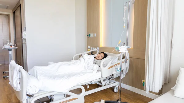 Female patient lying on an inpatient bed in the recovery room treating the illness and being closely monitored by a physician, Modern Adjustable Patient Bed in Hospital, Service point in a modern hospital
