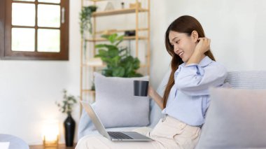 Woman using laptop to work or do homework at home with smiling face in her living room, Creating happiness at work with a smile, Live performance or video call with laptop, Work from home.