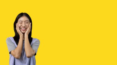 Asian woman smiling happily isolated on yellow background, Woman loves and rejoices herself, Contented, Pure love, Love myself, Proud of yourself, Self-made happiness, Optimism, Painting Therapy with a smile.
