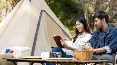Couple camping for the weekend in the woods near the river, Leisure and relaxation activities in the midst of nature, Man taking photo of woman to capture memories, Couple outdoor leisure activities.