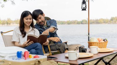Couple camping for the weekend in the woods near the river, Leisure and relaxation activities in the midst of nature, Man taking photo of woman to capture memories, Couple outdoor leisure activities.