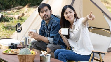 Young couple camping weekend in the woods near river, Enjoying Camping Holiday In Countryside, Leisure activities, Dating and relaxation in nature, Couple dripping coffee and sipping coffee.