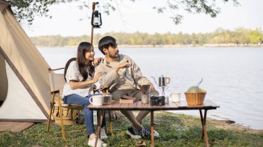 Couple camping for the weekend in the woods near the river, Camping Holiday In Countryside, Camping for the day and recreational activities amidst nature and relaxation, Outdoor leisure activities.